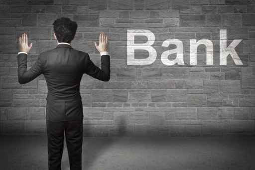 businessman standing in front of a wall hands up bank